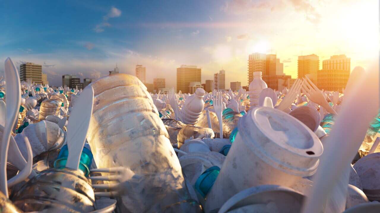 Piles of plastic waste with a cityscape in the background.