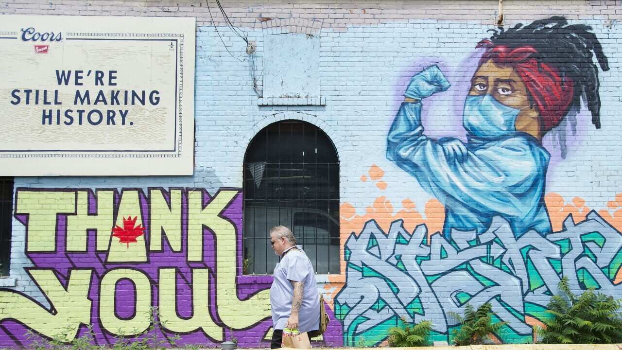 A man walks past a mural that pays tribute to health-care workers during the COVID-19 pandemic in Toronto on Wednesday, July 22, 2020. (Nathan Denette/The Canadian Press via AP)