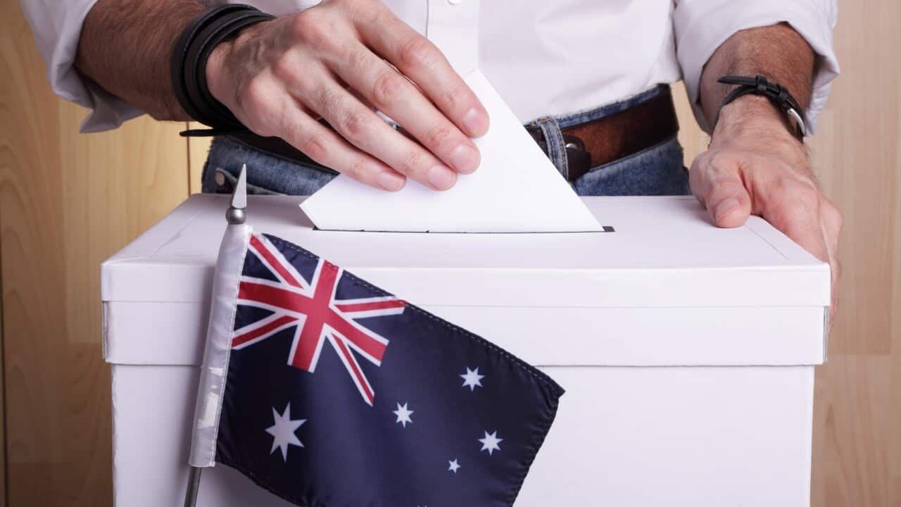 Un uomo inserisce una scheda elettorale in un'urna.