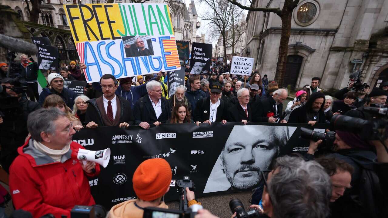 A crowd of protesters, some holding signs that read: "FREE JULIAN ASSANGE".