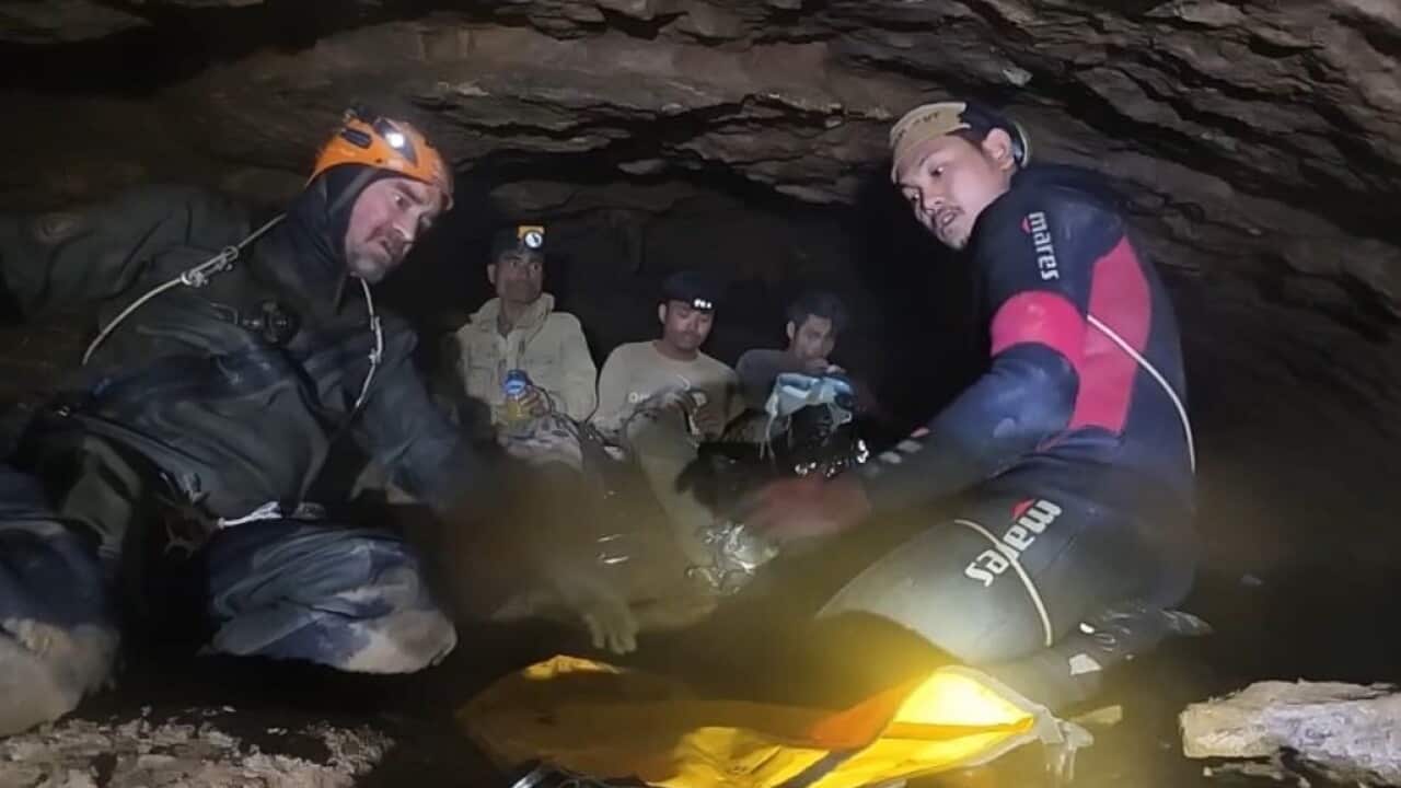 Men in diving equipment in the entrance of a cave