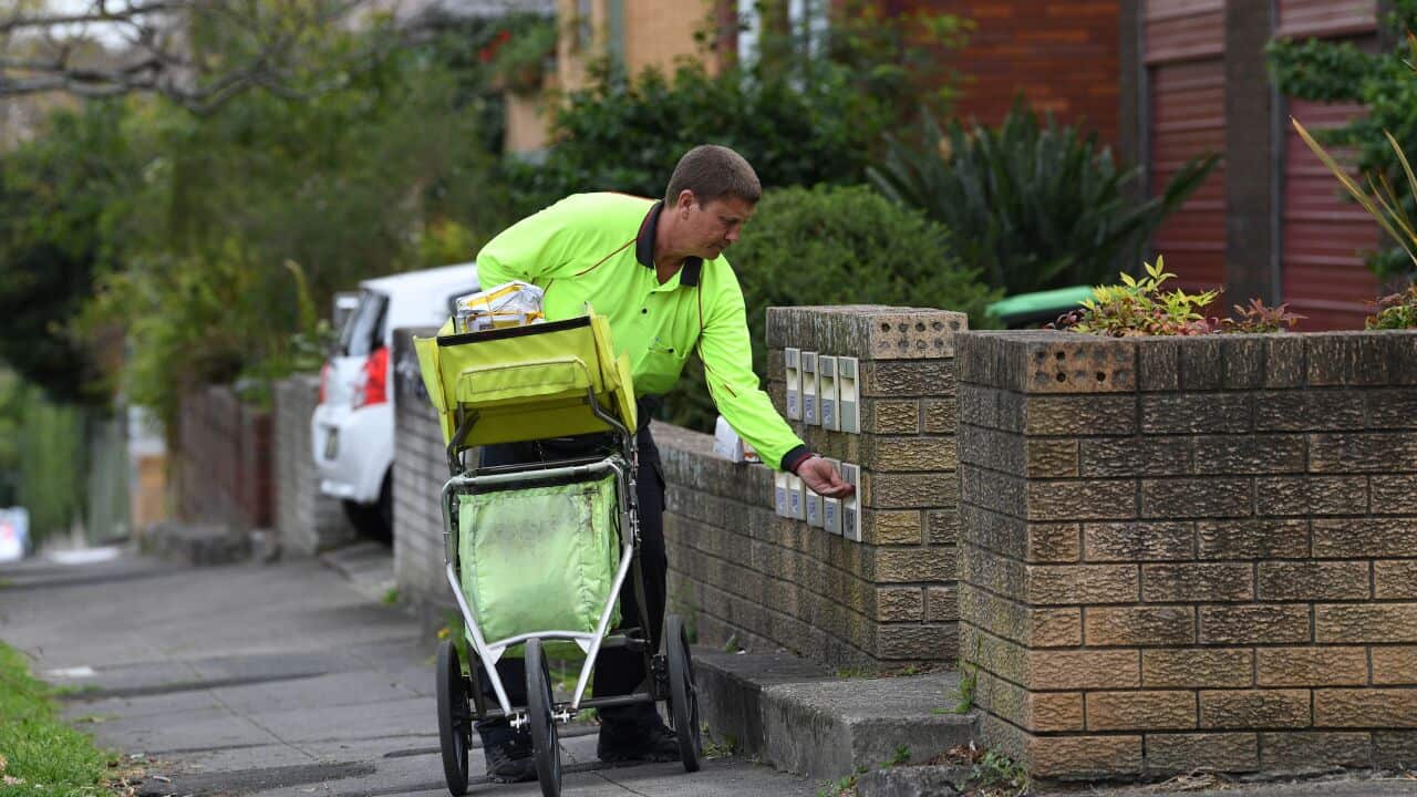 A man delivers a letter into a mailbox.