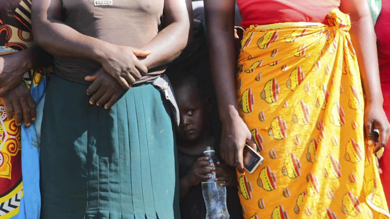 A child is seen between women waiting to receive food aid in Zimbabwe.