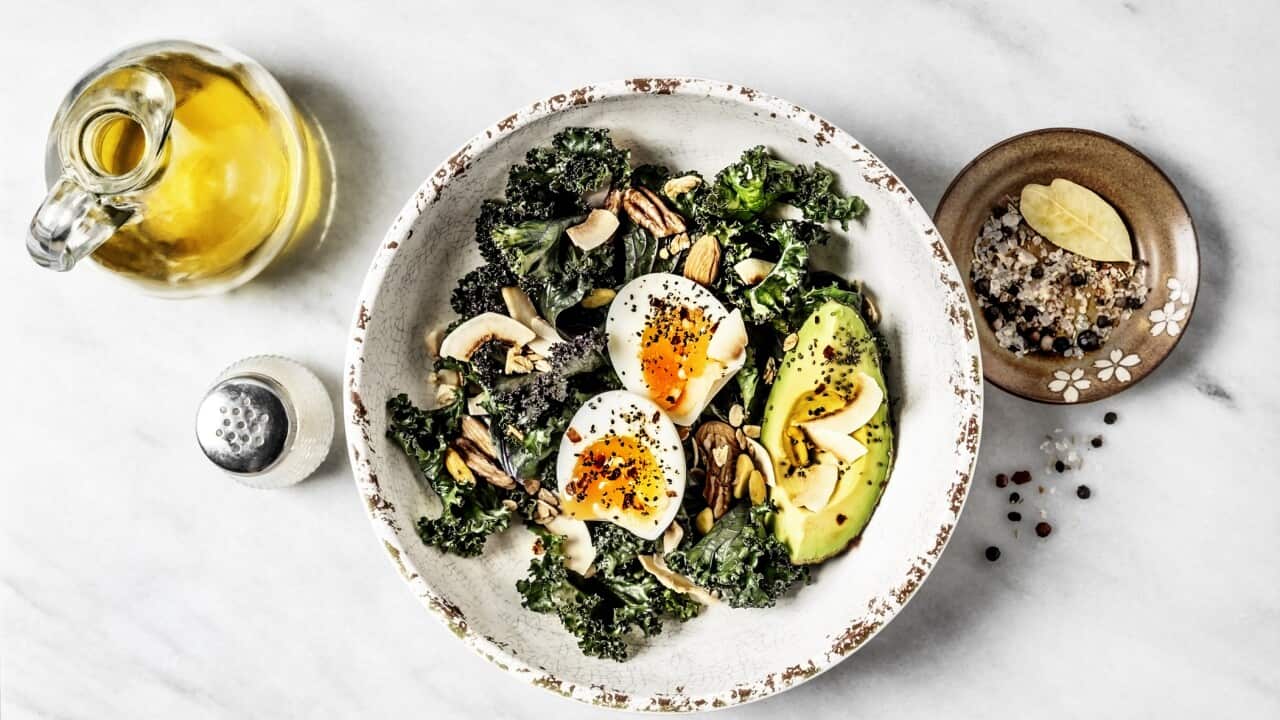 Bowl of kale salad with boiled eggs and avocado and olive oil