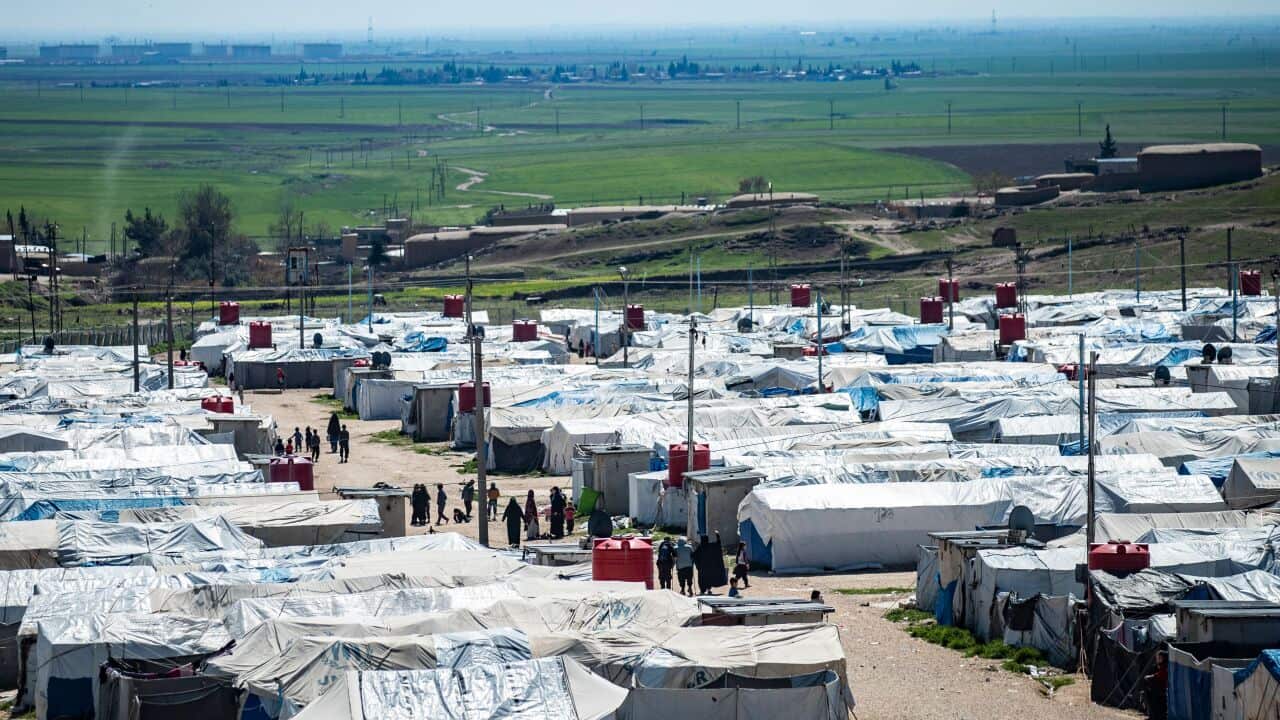 Aerial shot of refugee camp with rows of tents lined together, and people walking.