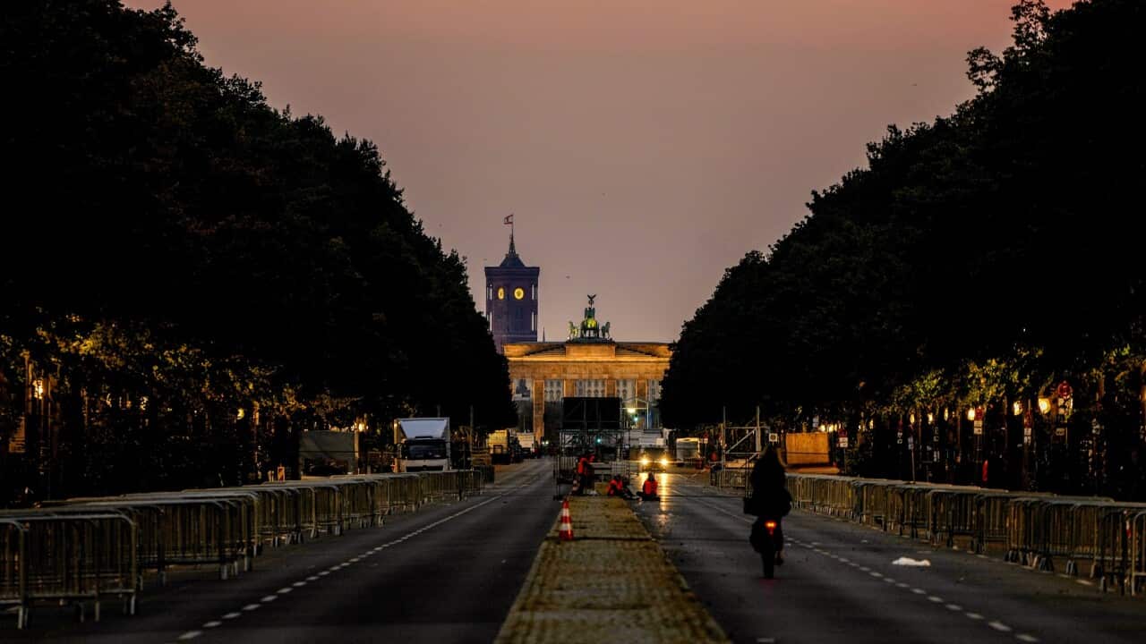 A man rides his bike towards the Brandenburg Gate in Berlin, Germany