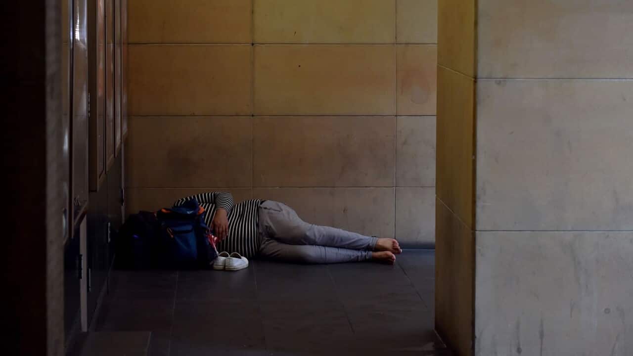 A woman sleeps in a doorway in Sydney's central business district.