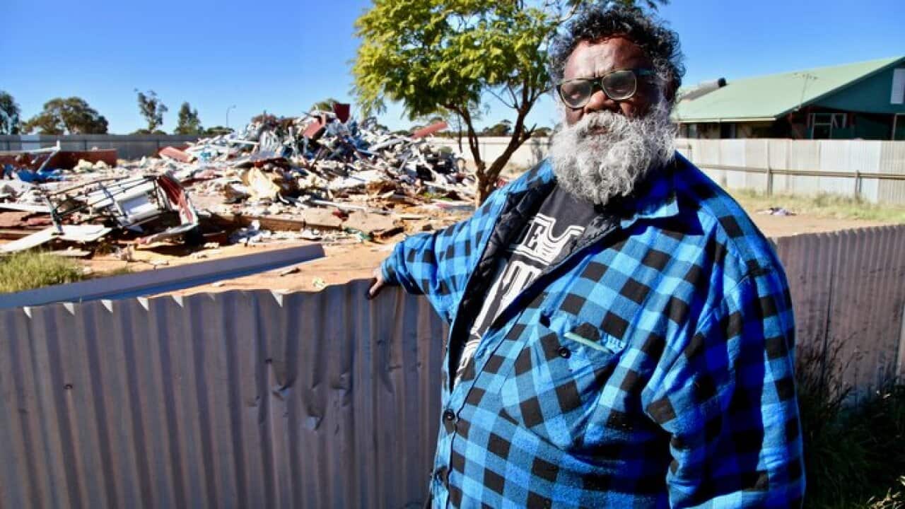 Pastor Geoffrey Stokes stands in front of a pile of debris in the village of Ninga Mia, WA