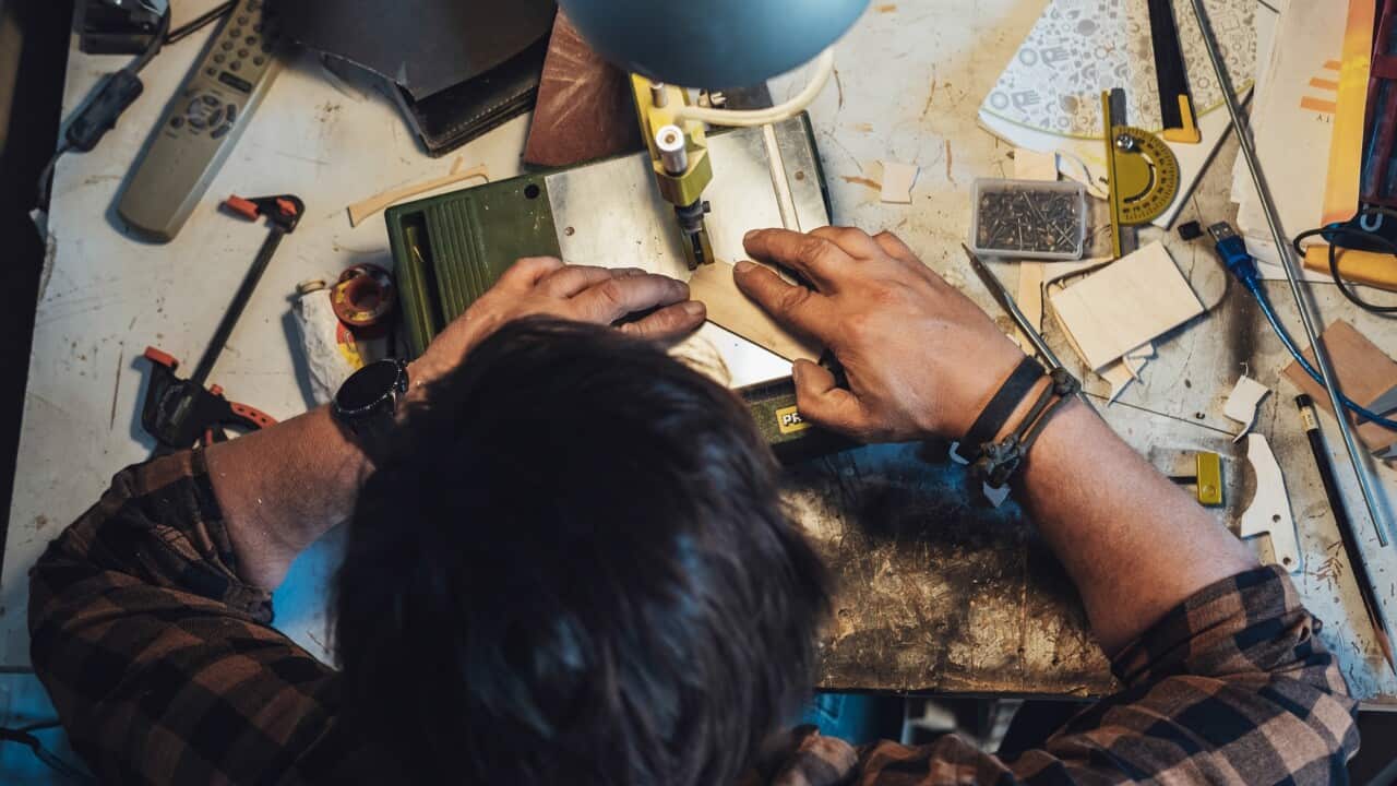 Table top view of unrecognizable man cutting a board on a table saw at his garage.