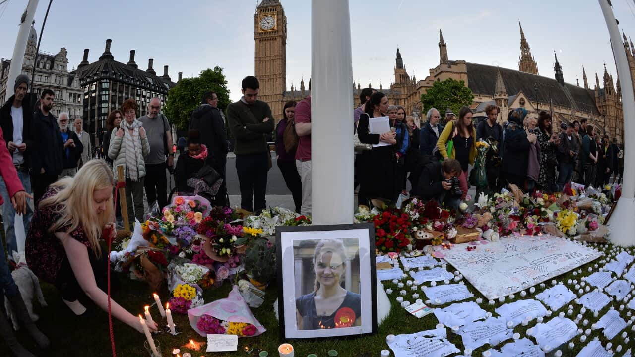 Members of the public look at flowers and tributes in Parliament Square, London