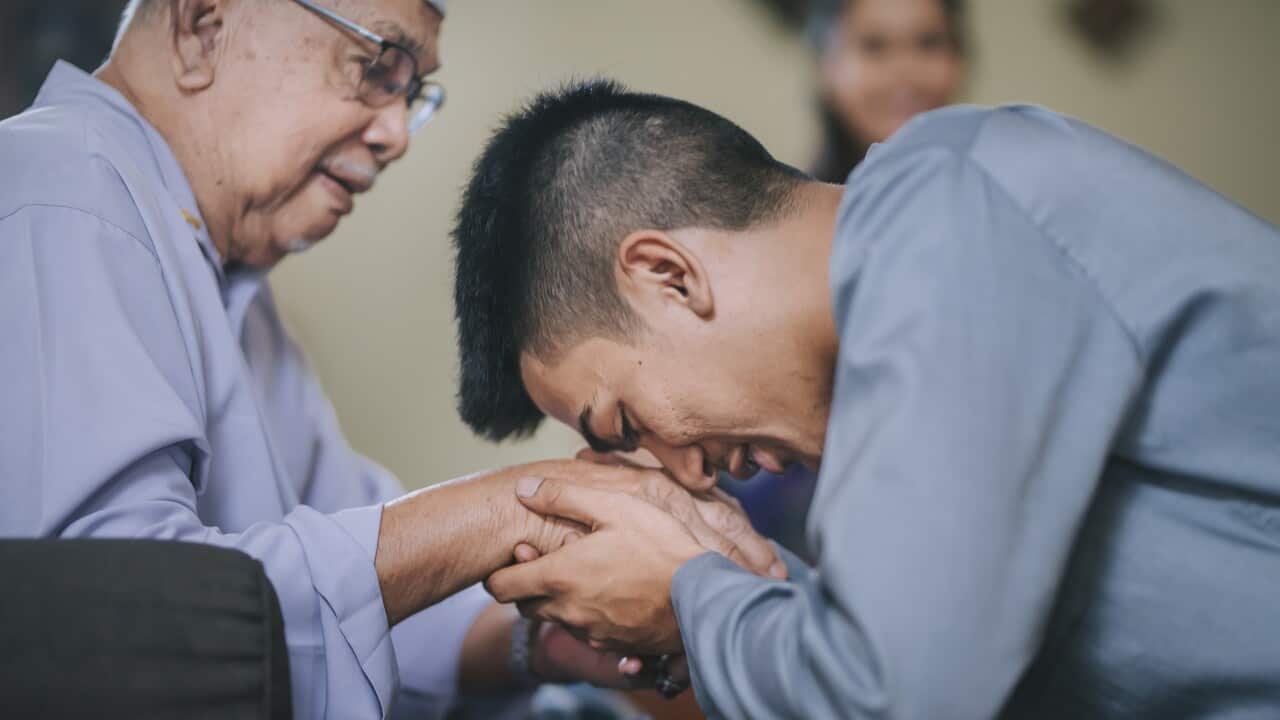 malay muslim grandson in traditional costume showing apologize gesture to his grandfather during Aidilfitri celebration malay family at home celebrating hari raya