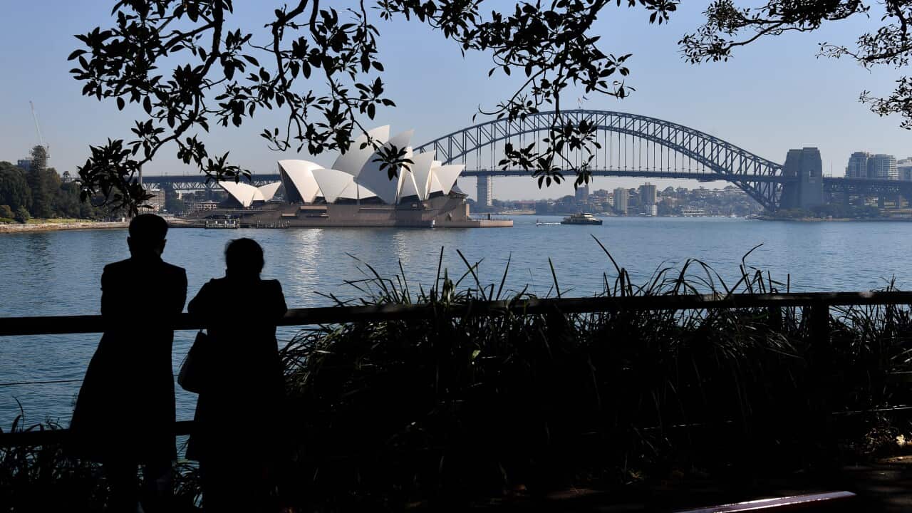 People standing and looking out at the Sydney Opera House and Sydney Habour Bridge.