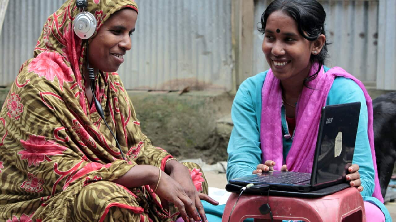 A woman helps Amina Begum to talk with her husband on Skype.