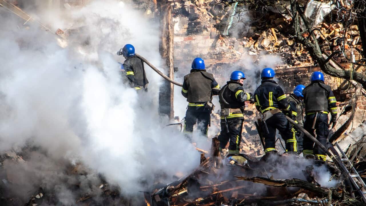 Group of firefighters standing amongst debris and smoke