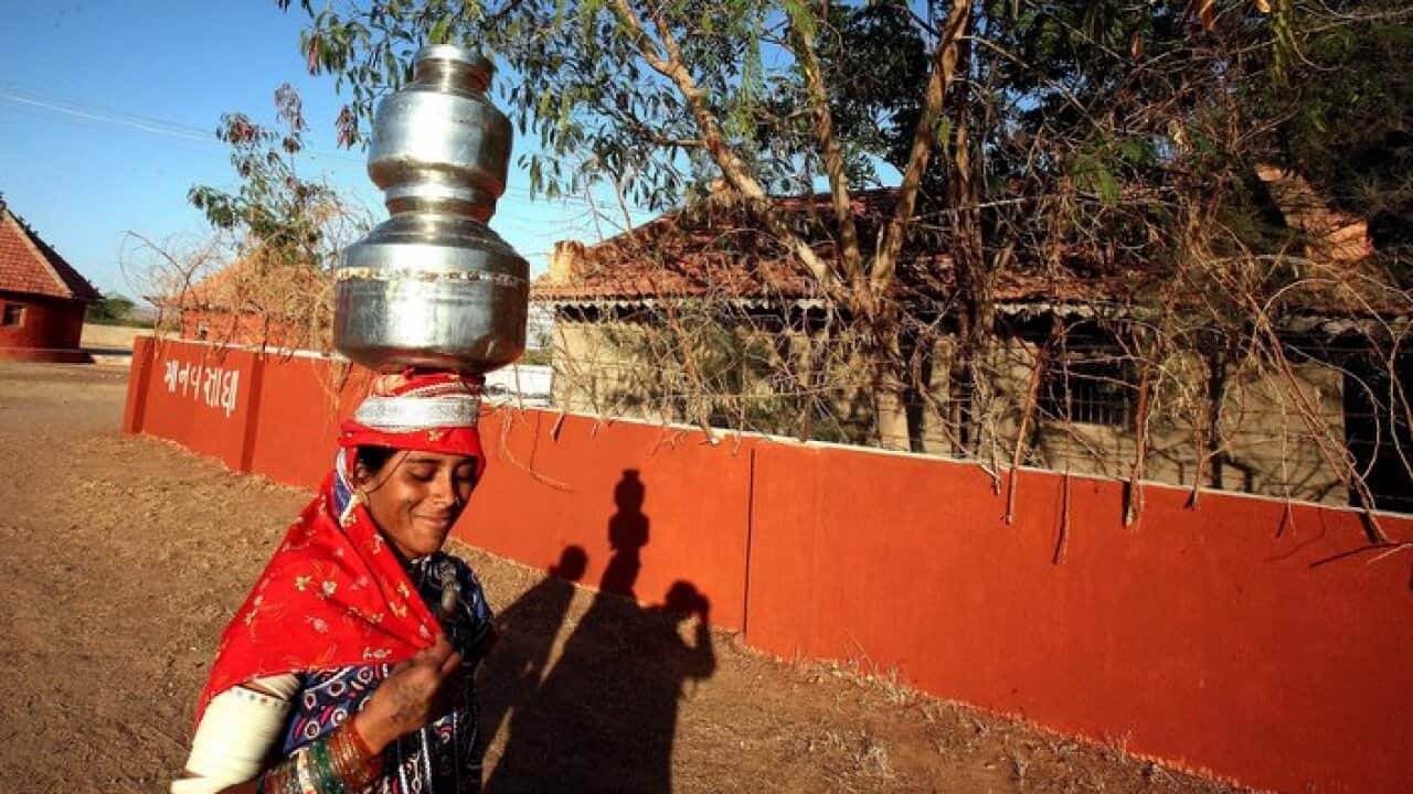 A woman walks to her cottage after collecting water from a well at Ludiya village of Kutch district which is about 70 kms from Bhuj.