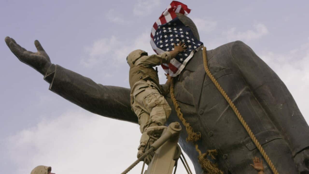 U.S. marine cover the face of a statue of Saddam Hussein with an American flag before toppling the statue downtown in Bagdhad