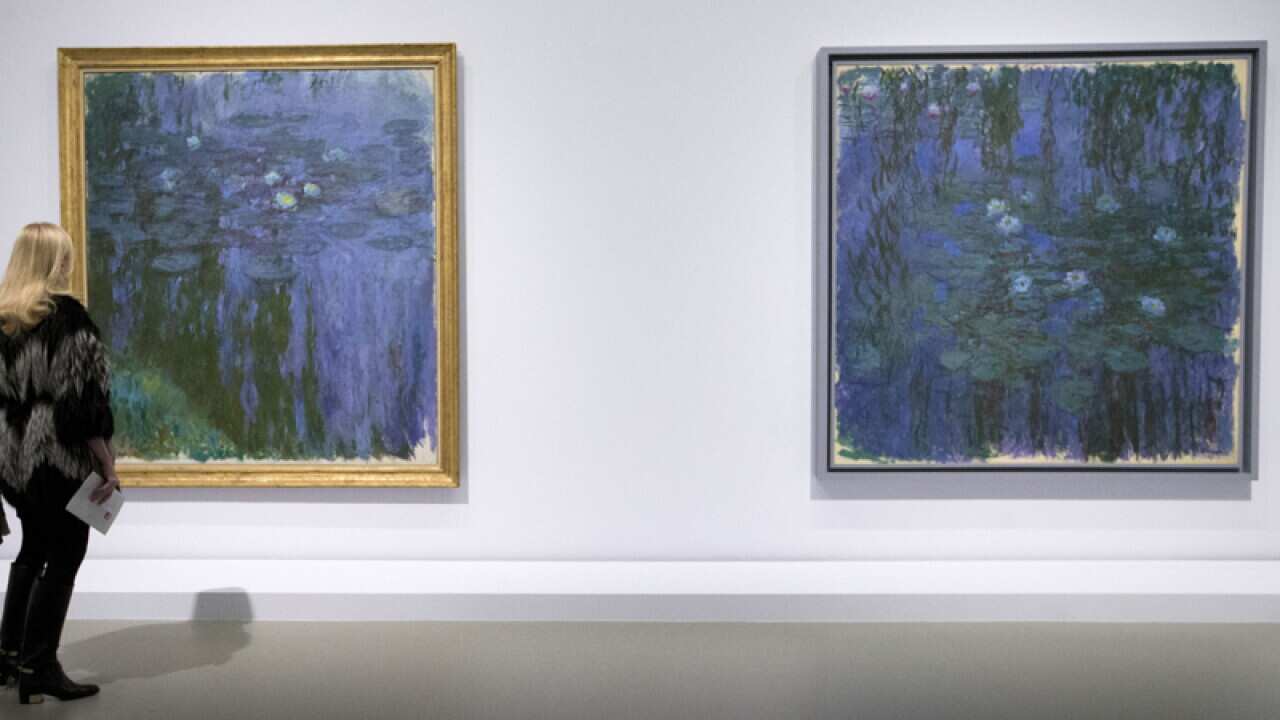 A visitor looks at Blue Water Lilies, and Water Lilies of Claude Monet