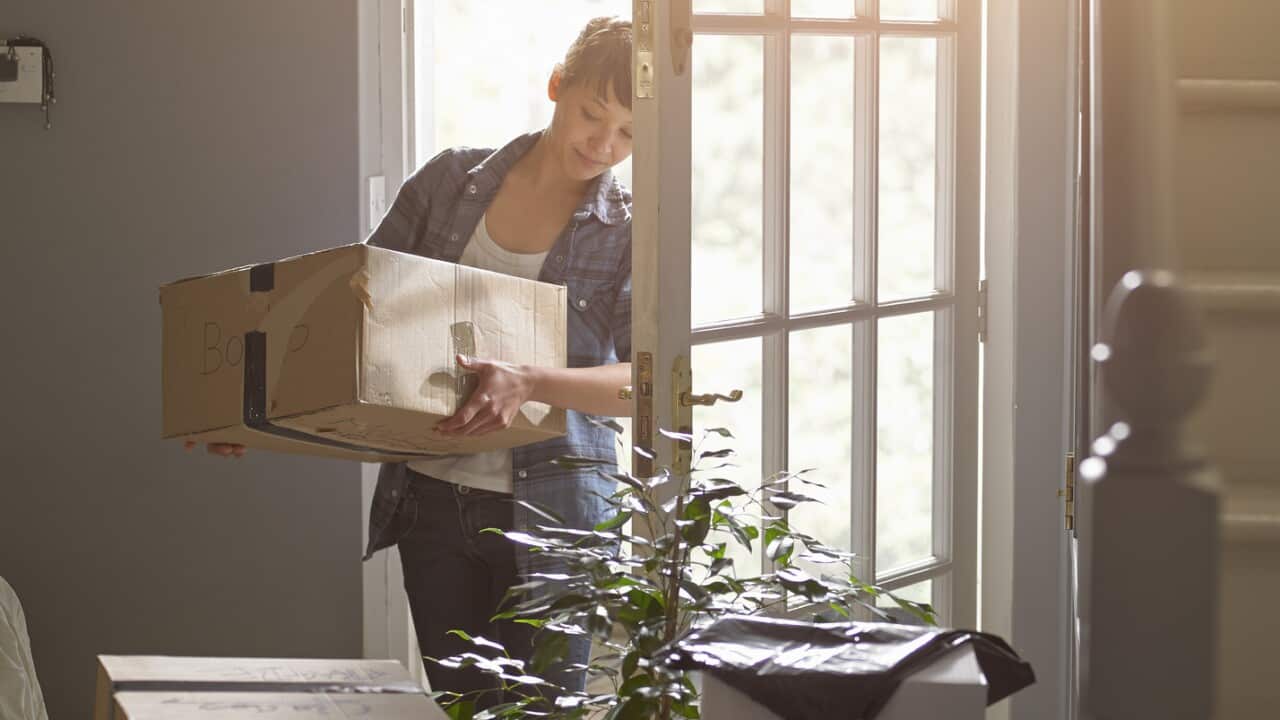 And woman carrying a packing box into her new home