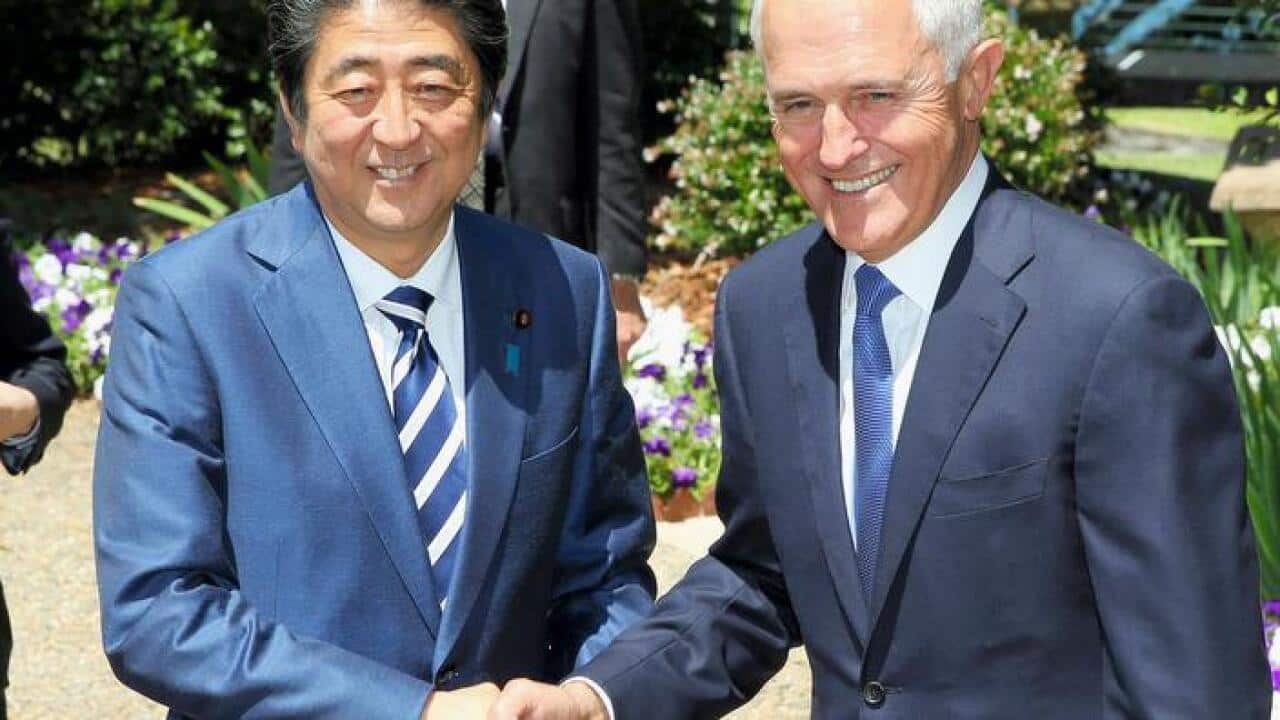 PMs of Australia and Japan shake their hands.
