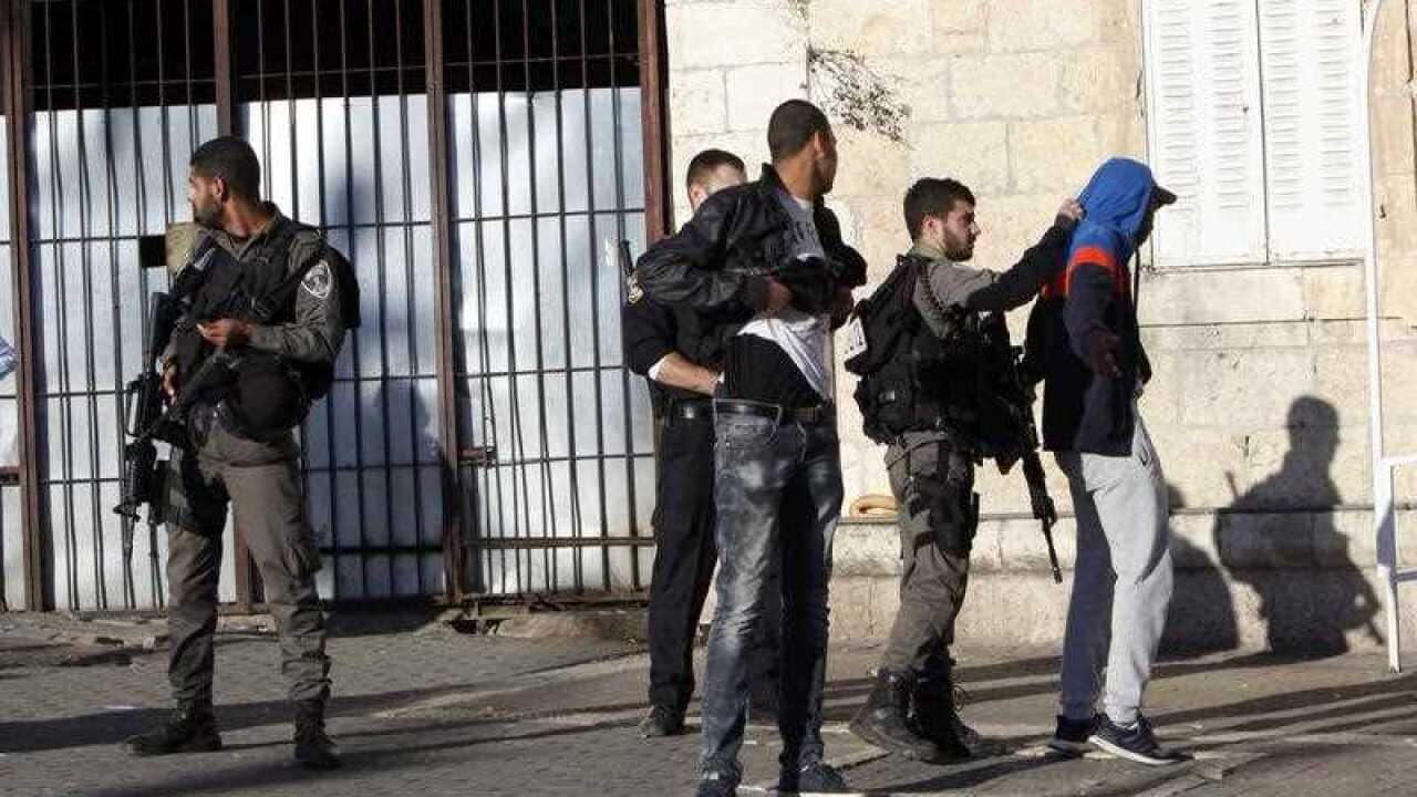 An Israeli police officer stands guard as others check a Palestinian near the scene of a shooting attack near the Damascus gate, Jerusalem's Old City, Wednesday, Feb. 3, 2016.