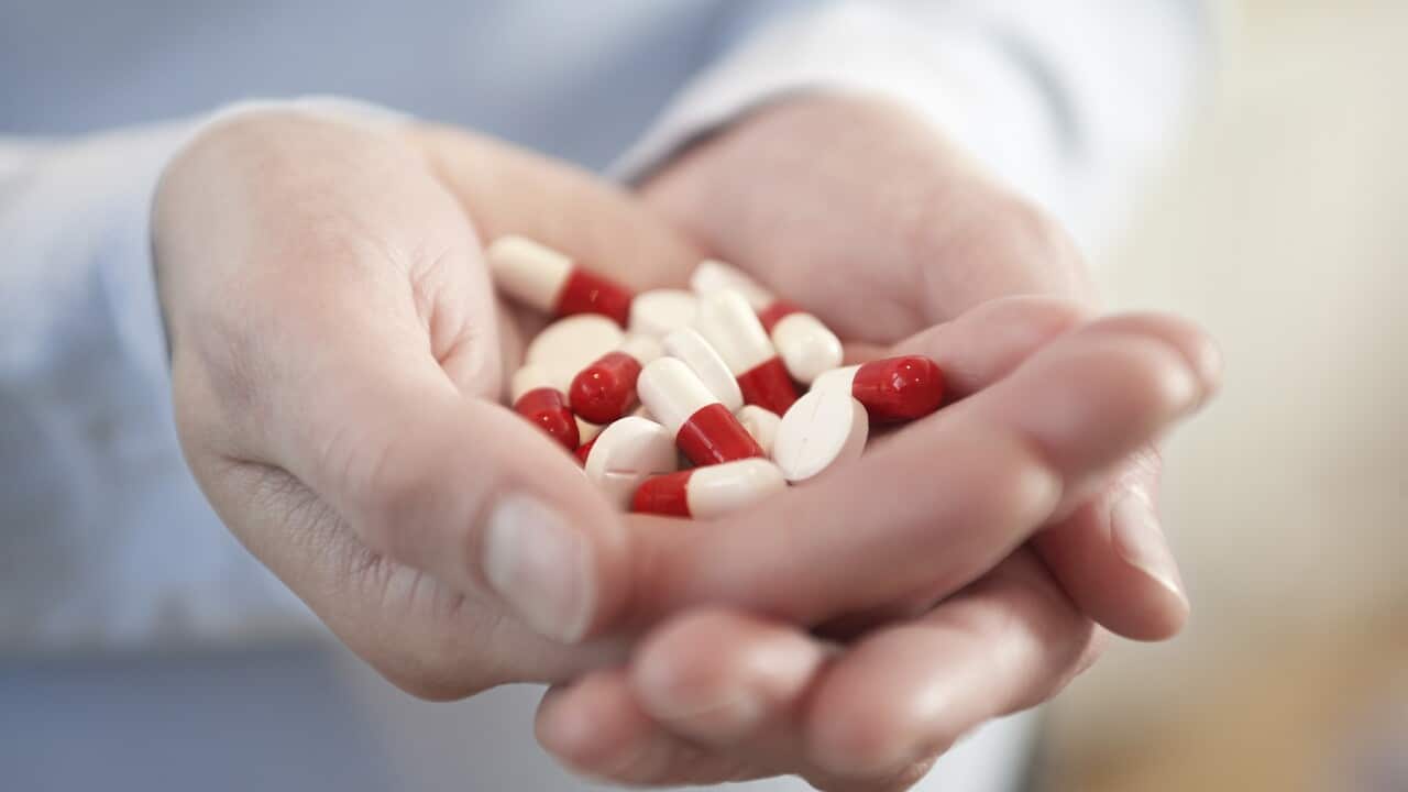 Woman holding medicine pills in clasped hands close up on hands