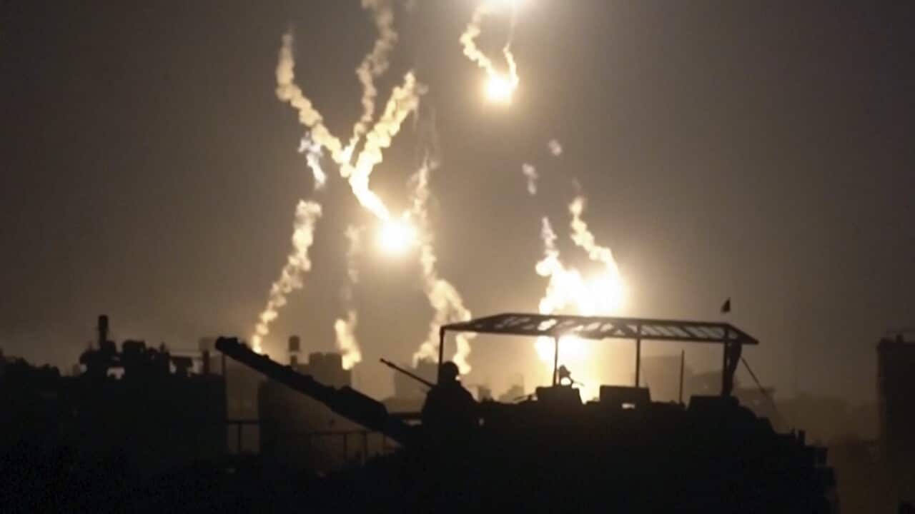 Israeli soldiers are illuminated at night by flares in Gaza