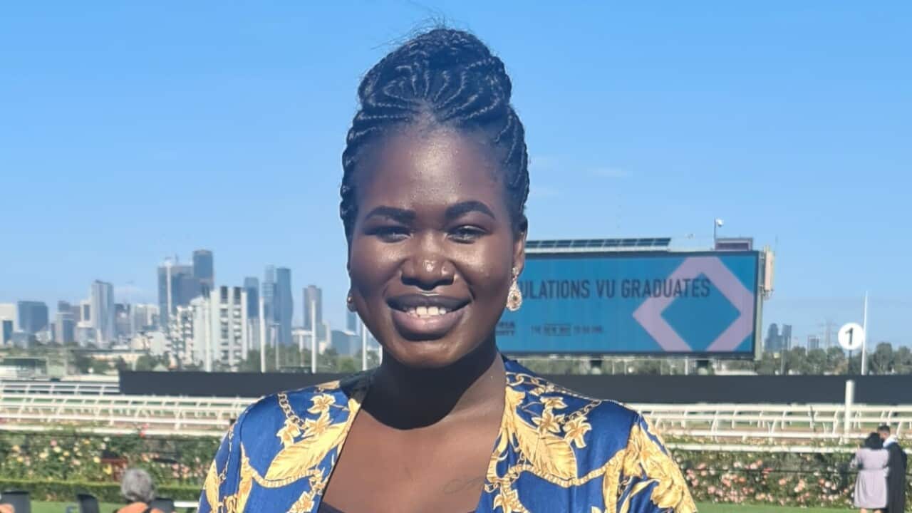 Arok Deng wearing a blue and yellow patterned outfit and standing outside