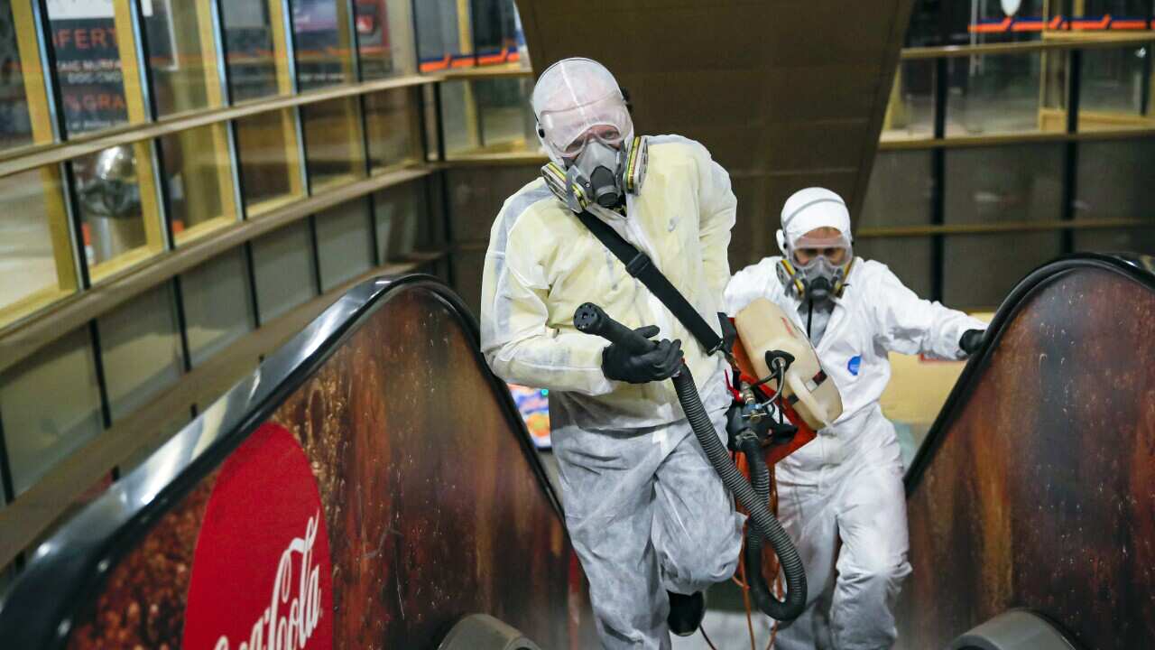 Men wearing protective gear spray chemicals during the disinfection of a popular market, part of the efforts to limit the spread of the Coronavirus