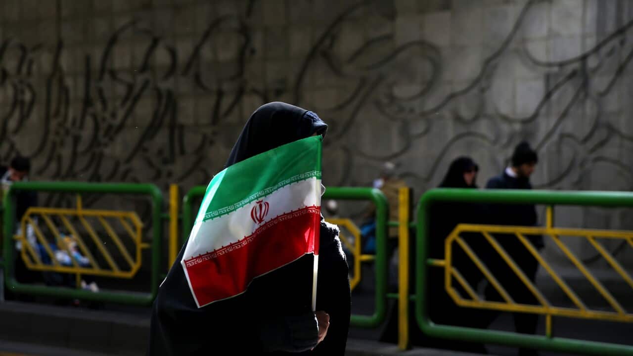 An Iranian woman holds the national flag