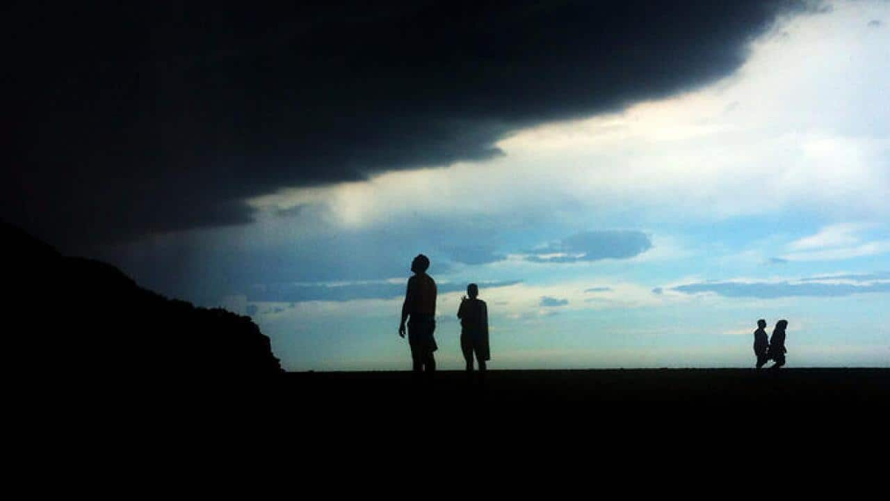 Beach goers watch as a thunderstorm moves in over Stanwell Park beach south of Sydney, Sunday, Dec. 7, 2014. Sydney has been hit by severe thunderstorms for the past week. (AAP Image/Dean Lewins) NO ARCHIVING