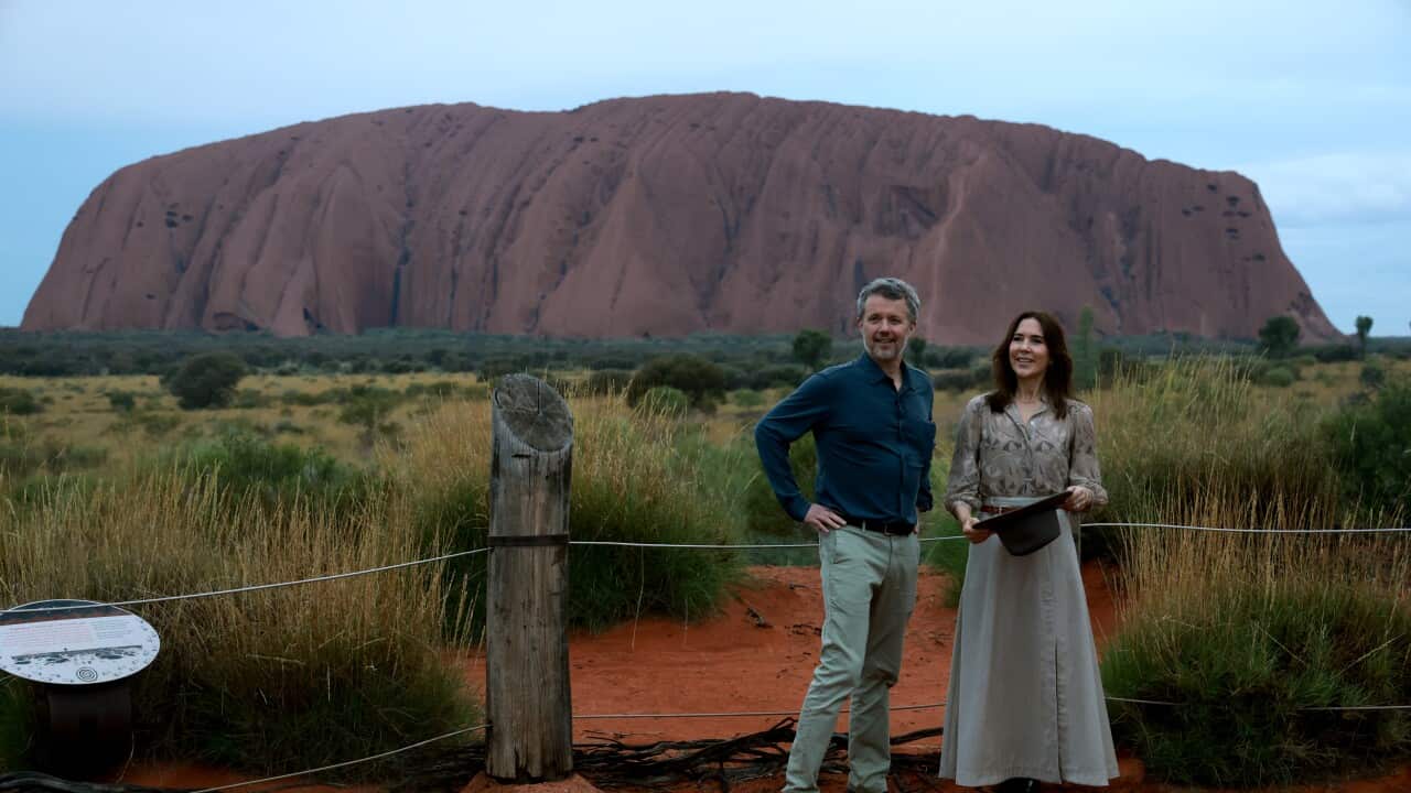 A man and a woman pose for a photo with a red mountain in the background