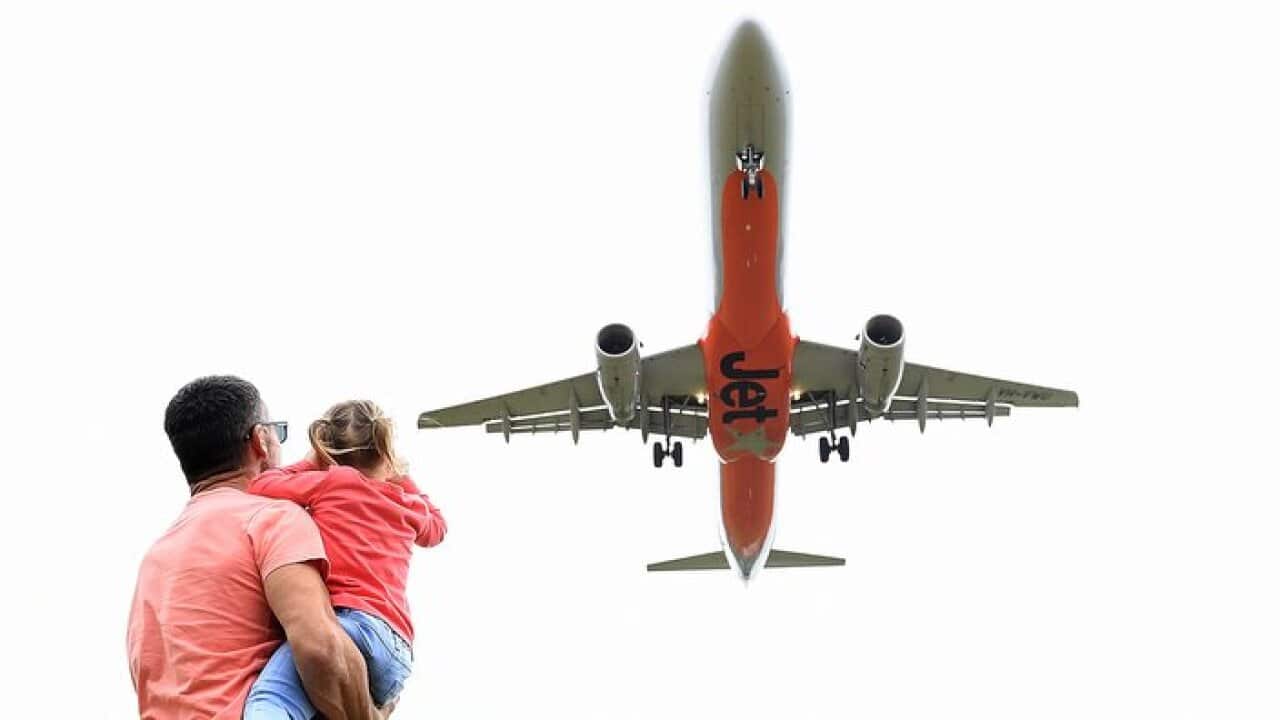 A father and daughter look on as a Jetstar aircraft passes by on the Gold Coast, Saturday, May 13, 2017