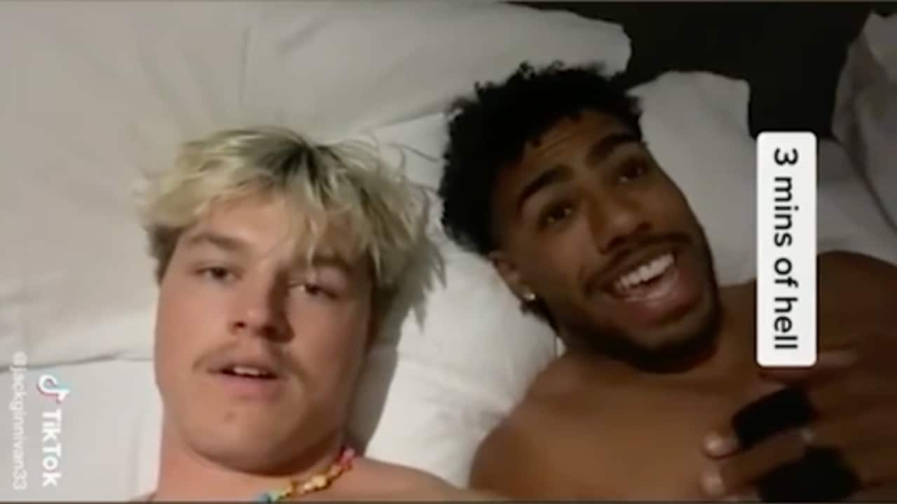 Two men laughing in bed.