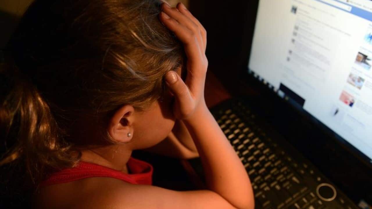 an upset young girl in front of a personal computer
