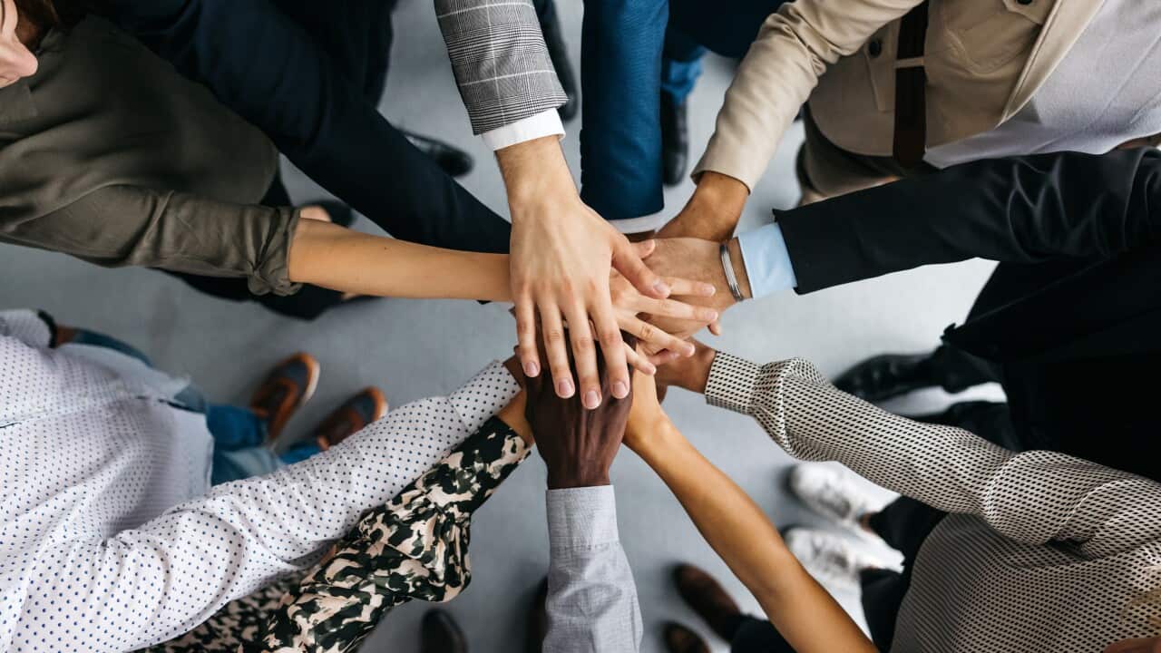 Close-up of co-workers stacking their hands together