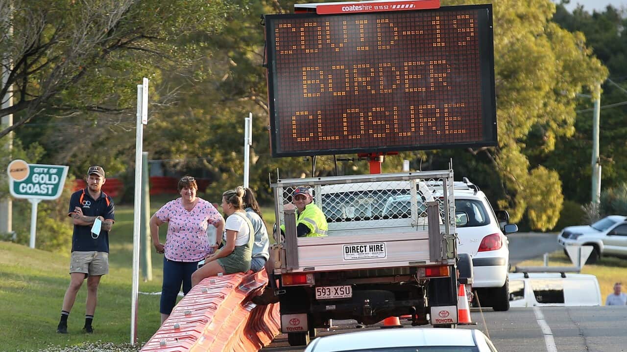 People talk to each other over the barriers at the QLD/NSW border at Tweed Heads, Gold Coast.