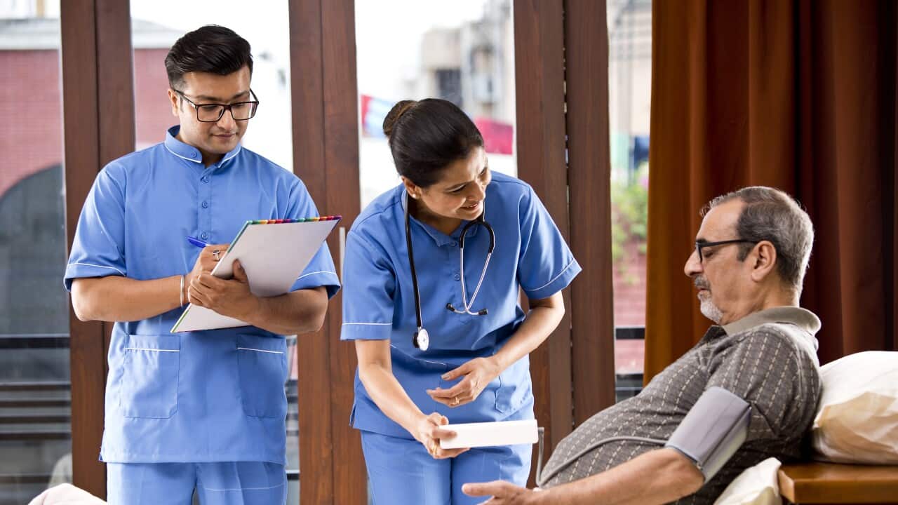 Male and female nurse checking senior man's blood pressure on house call