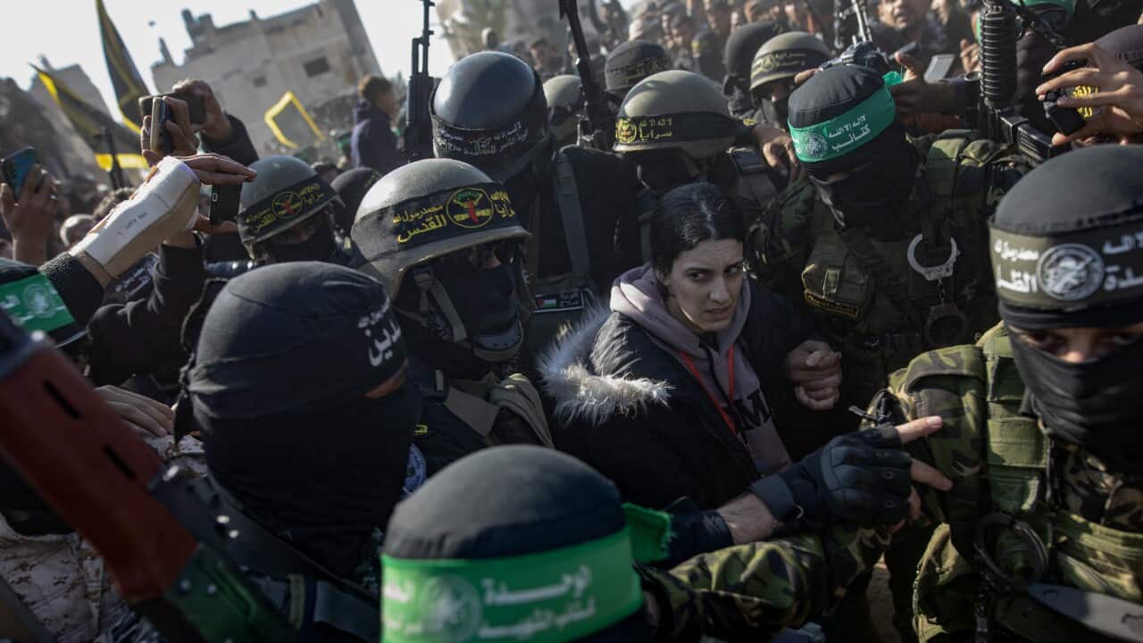 A woman, surrounded by armed men in uniforms, looks terrified.