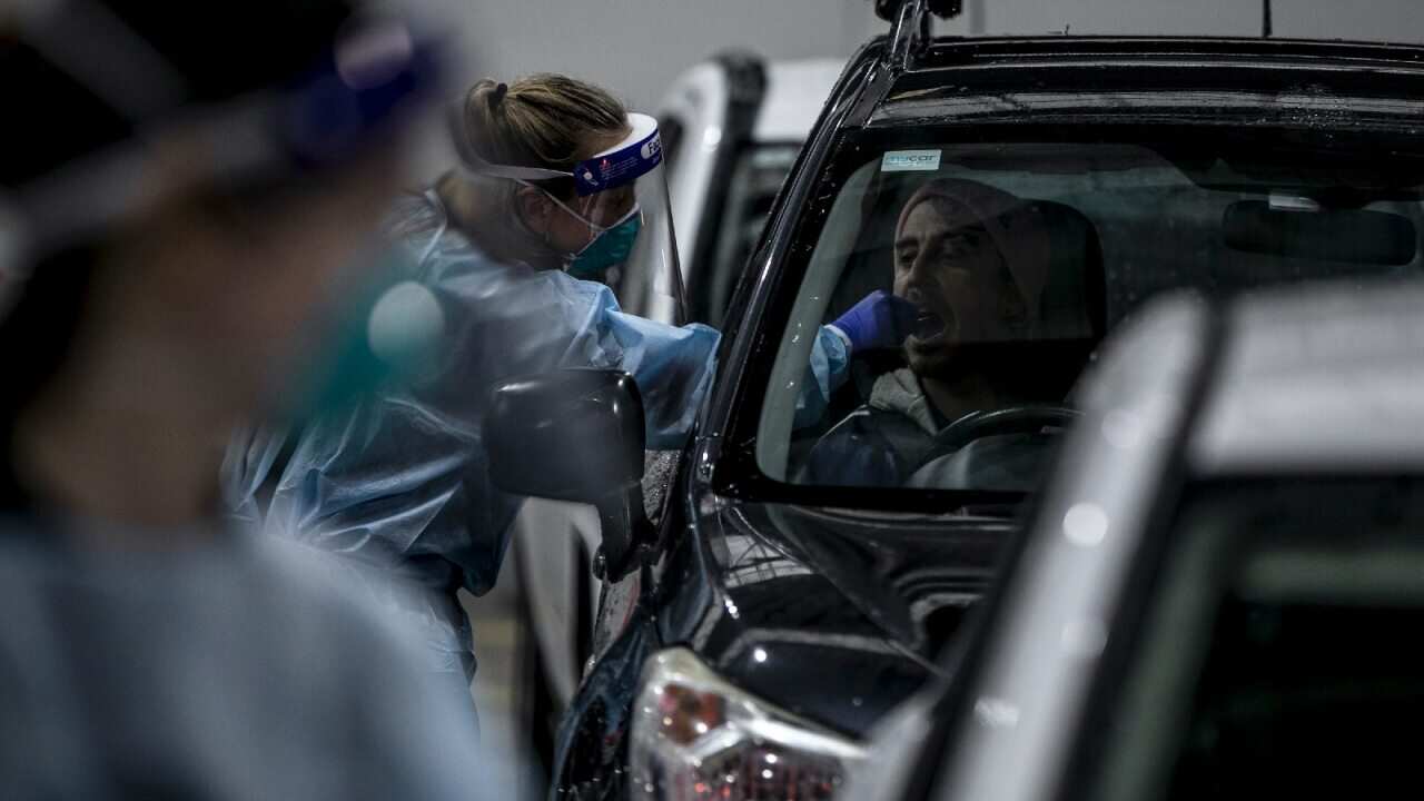 A health worker takes a throat swab sample of a man for a COVID-19 test at the drive through COVID-19 testing point Montague in Melbourne.