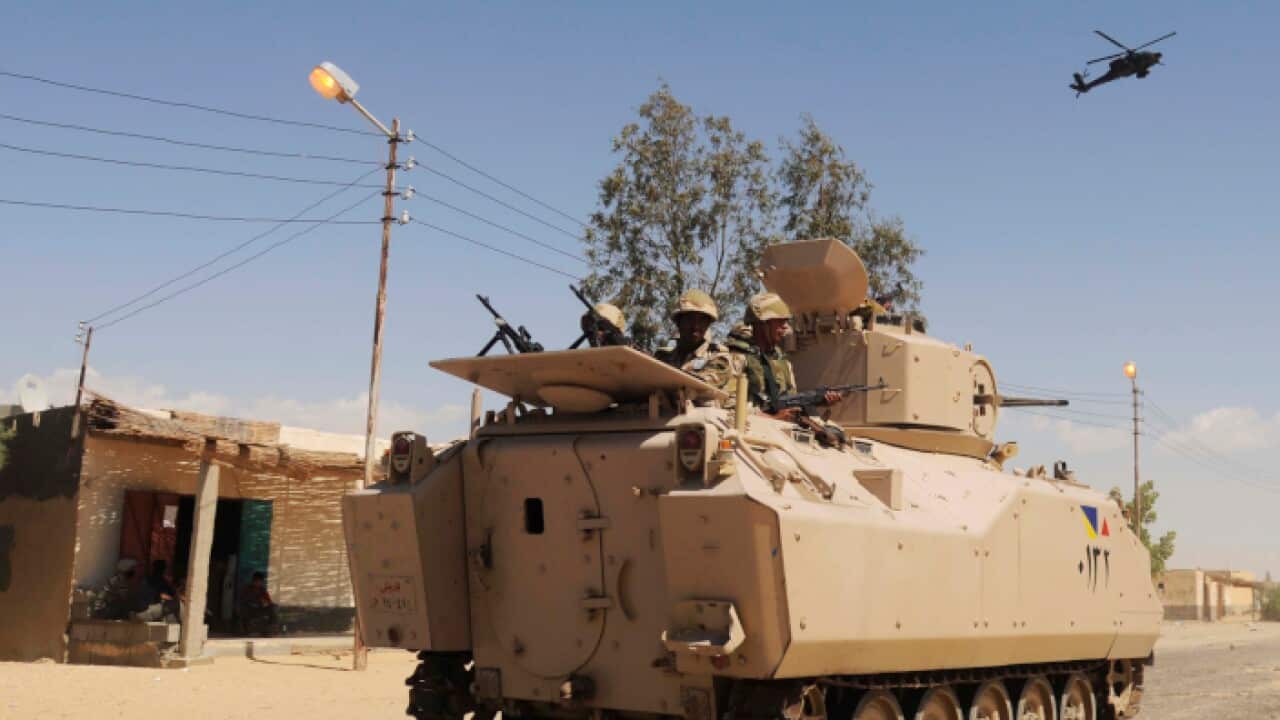 Egyptian Army soldiers patrol in an armored vehicle backed by a helicopter gunship during a sweep through villages in Sheikh Zuweyid, north Sinai, Egypt