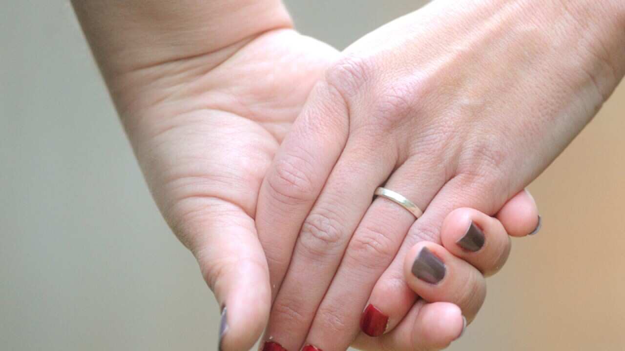 Women hold hands in Canberra