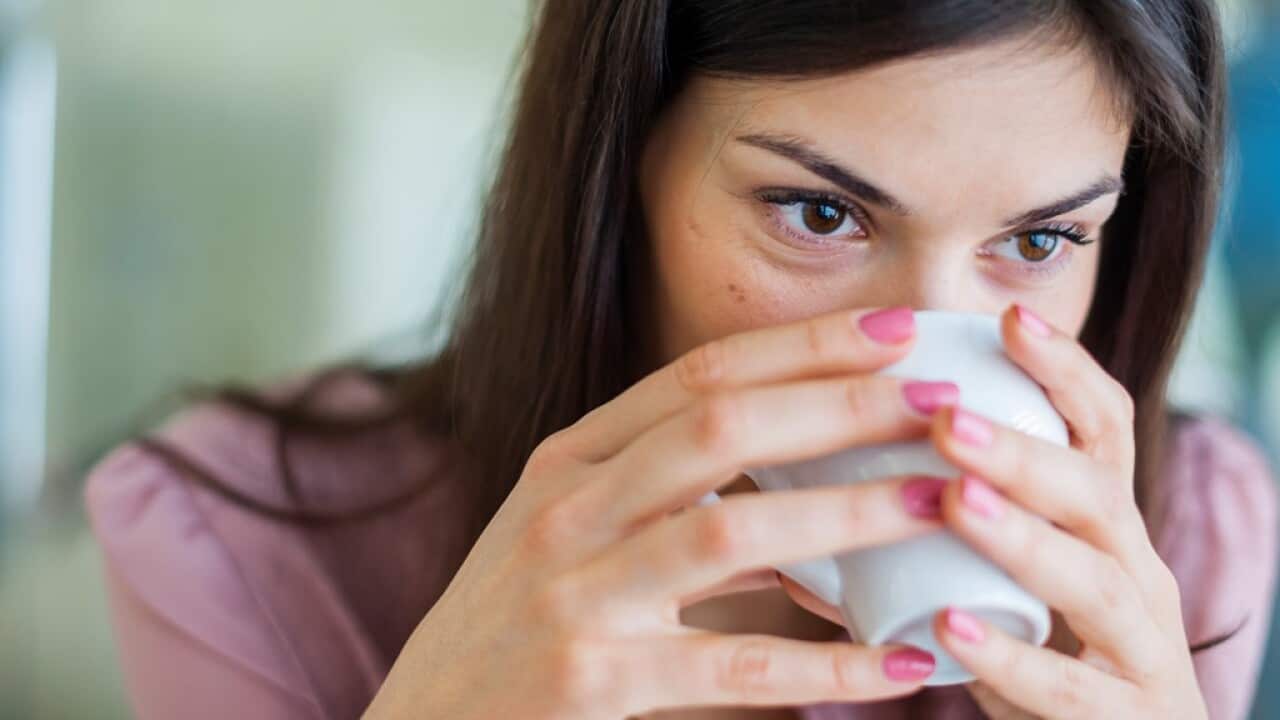 Young businesswoman having coffee in office