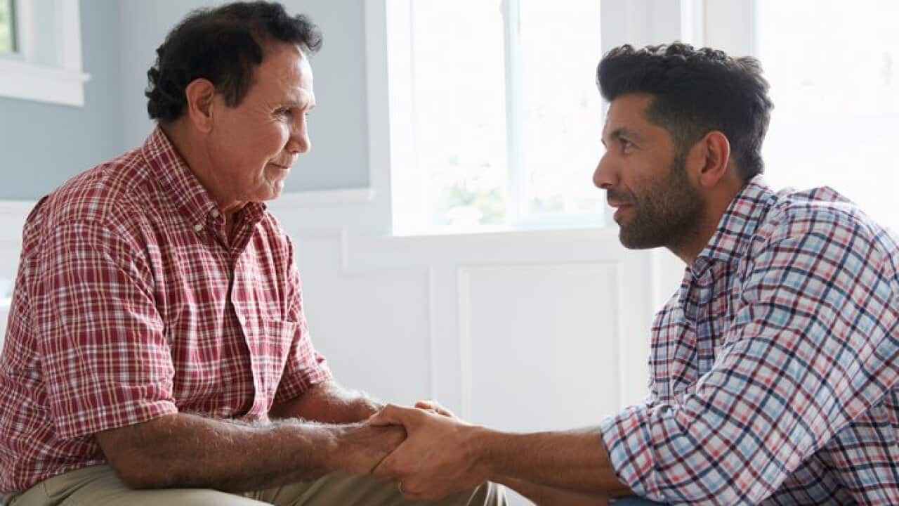 Adult Son Comforting Father Suffering With Dementia
