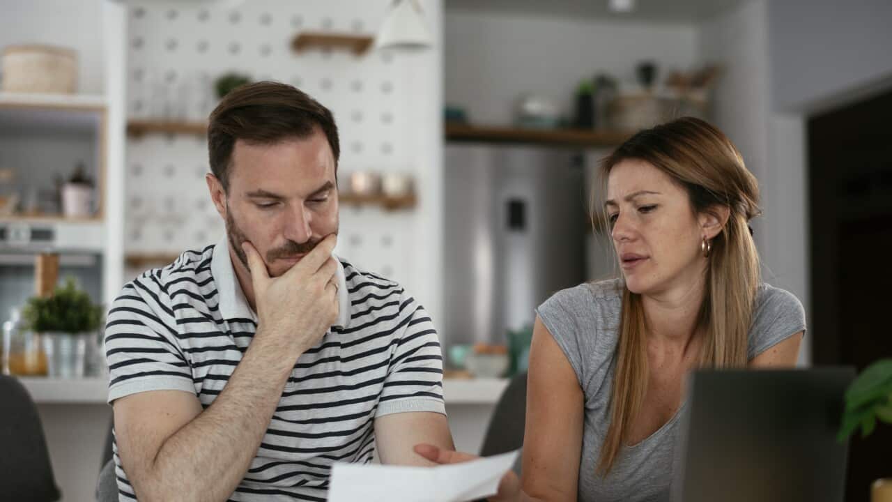 A couple with concerned facial expressions looking at a bill.