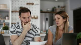 A couple with concerned facial expressions looking at a bill.