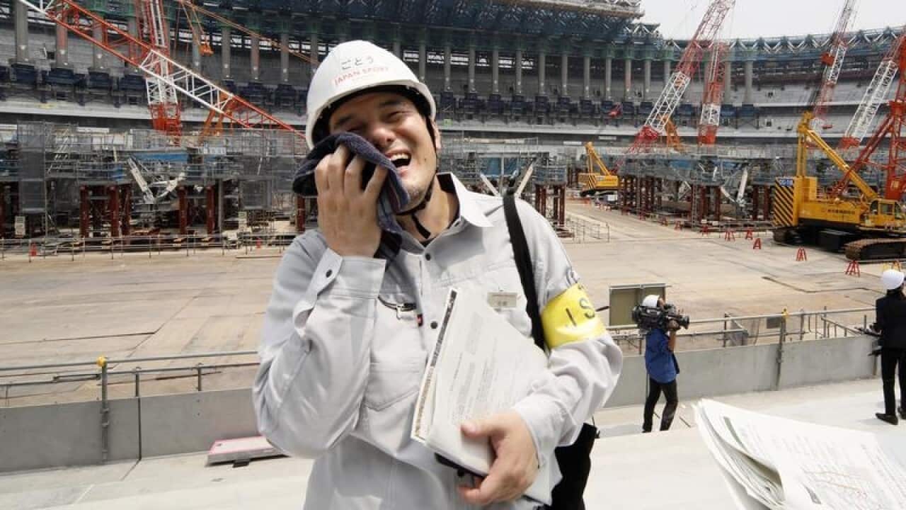 A Japan Sport Council staff wipes sweat on his face.