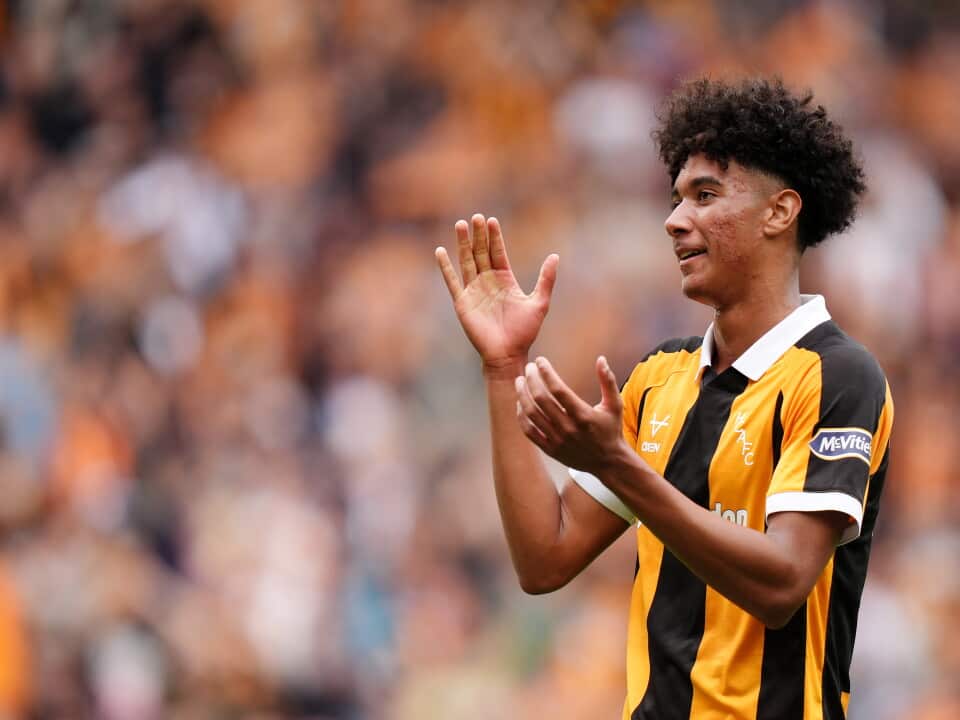 A man in a black and gold sports shirt claps