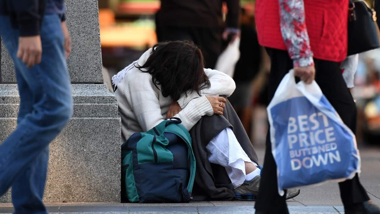 A homeless woman sits on a street corner in central Brisbane, Friday, June 9, 2017. (AAP Image/Dan Peled) NO ARCHIVING