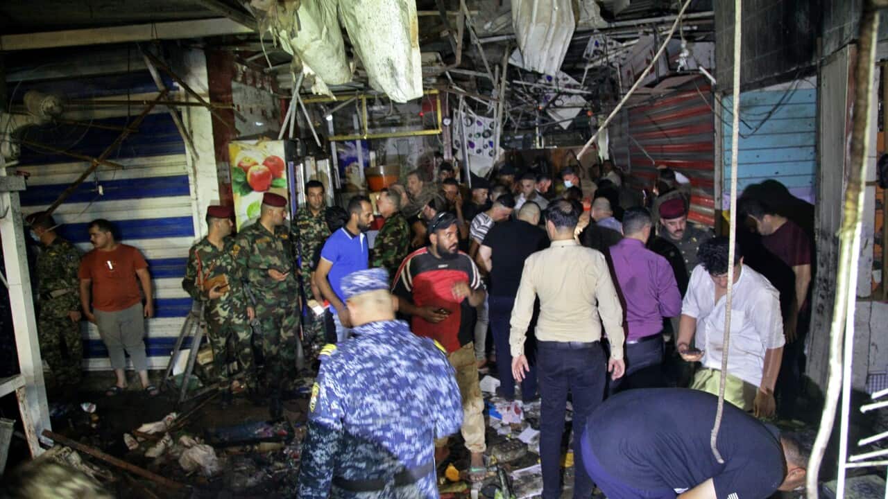 People and security forces gather at the site of a bombing in Wahailat market in Sadr City, Iraq, 19 July, 2021.