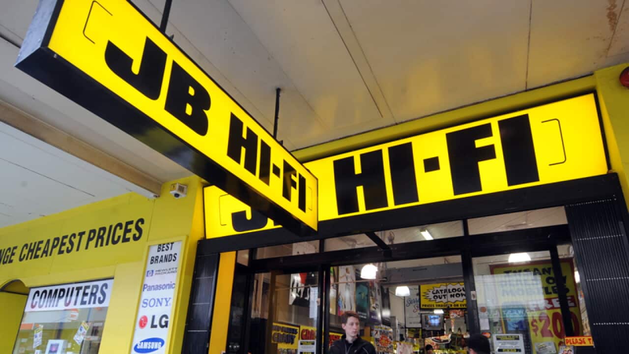 Pedestrains walk past a JB HI-FI store in Melbourne